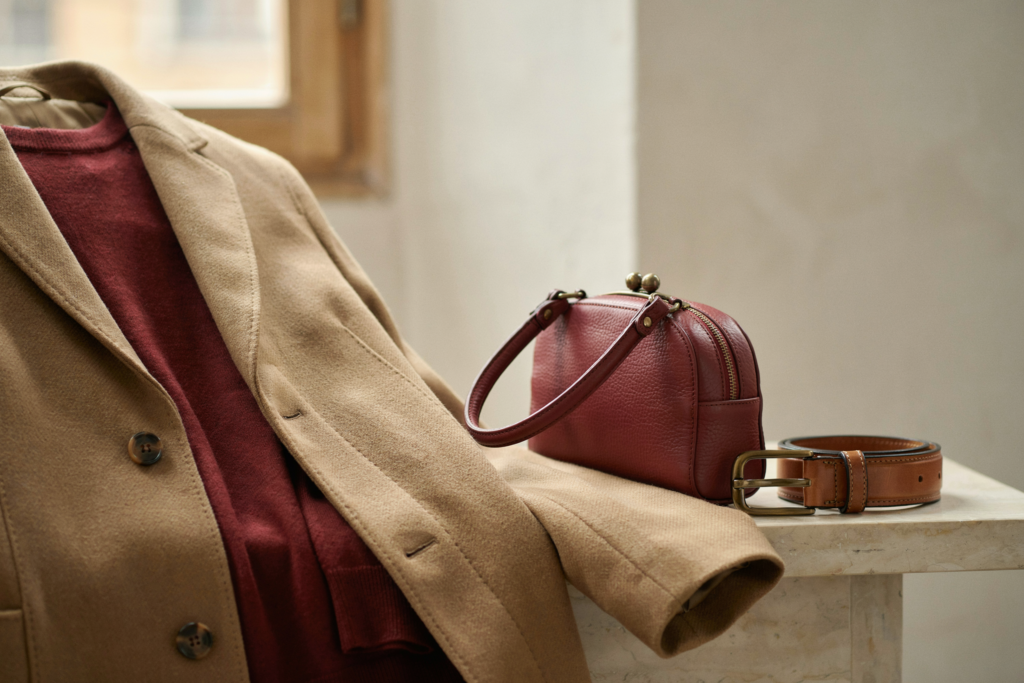 Dettaglio texture: maglione bordeaux sotto un cappotto color cammello, con borsa bordeaux coordinata - abbinamento bordeaux e cammello